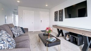 A modern living room with a sofa, coffee table, and a flat-screen TV mounted on the wall. - 2 Adjoining Condos Rent Together (Bozeman)