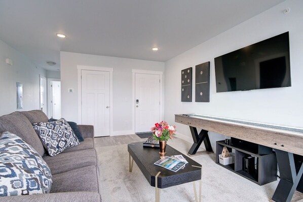 A modern living room with a sofa, coffee table, and a flat-screen TV mounted on the wall.