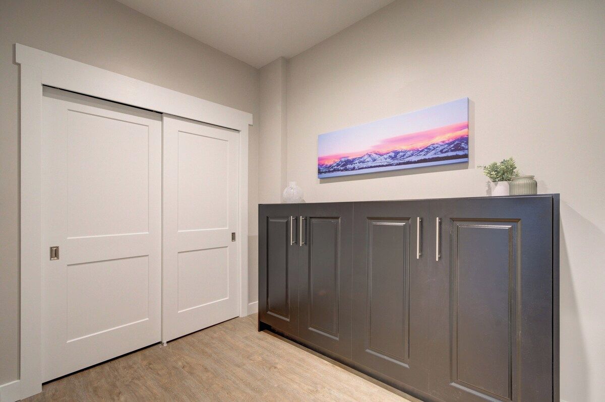 A hallway with a double door, a dark wooden cabinet, and a landscape painting on the wall.