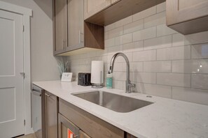 A modern kitchen with two sinks, a dishwasher, and wooden cabinets. - Cozy Downtown Condo (Bozeman)