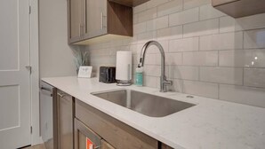 A modern kitchen with a double sink, stainless steel faucet, and a white countertop. - Cozy Downtown Condo (Bozeman)