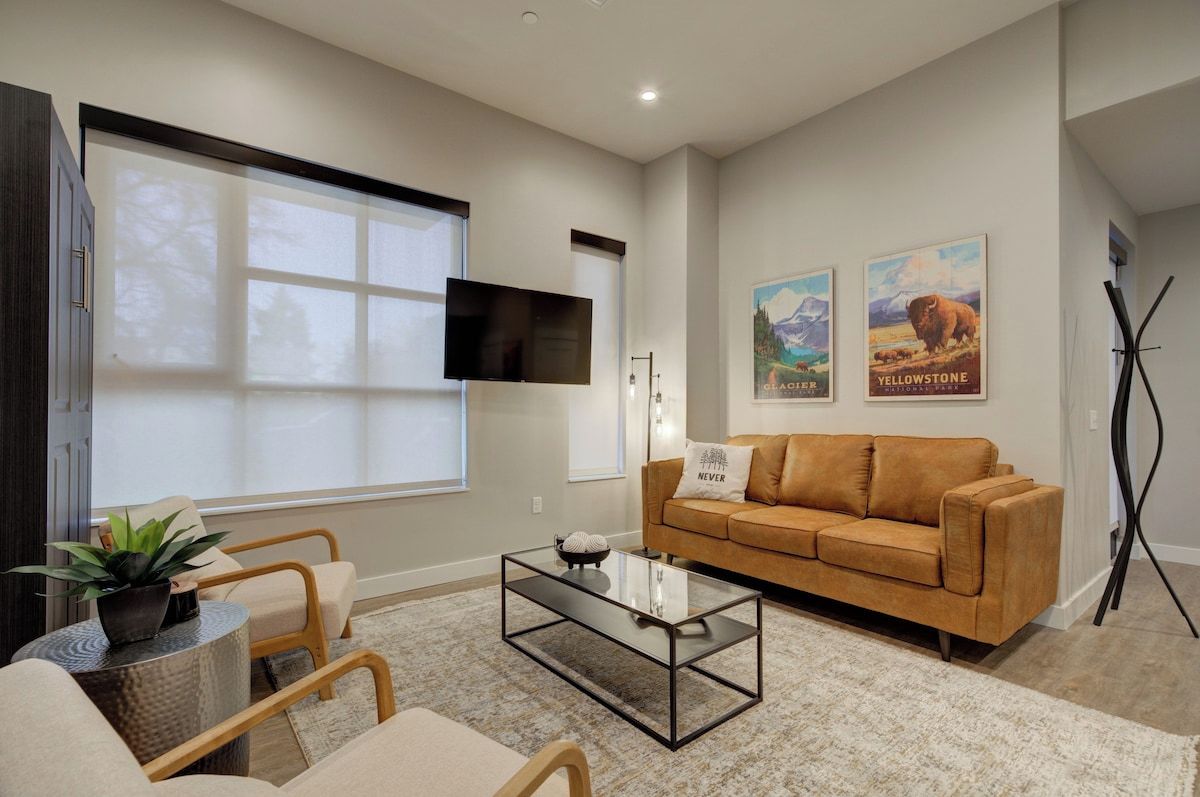 A modern living room with a sofa, coffee table, and a flat-screen TV mounted on the wall.