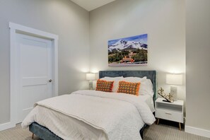 Ein Schlafzimmer mit einem Bett, Nachttischen, einem Wandbild und einer Tür.