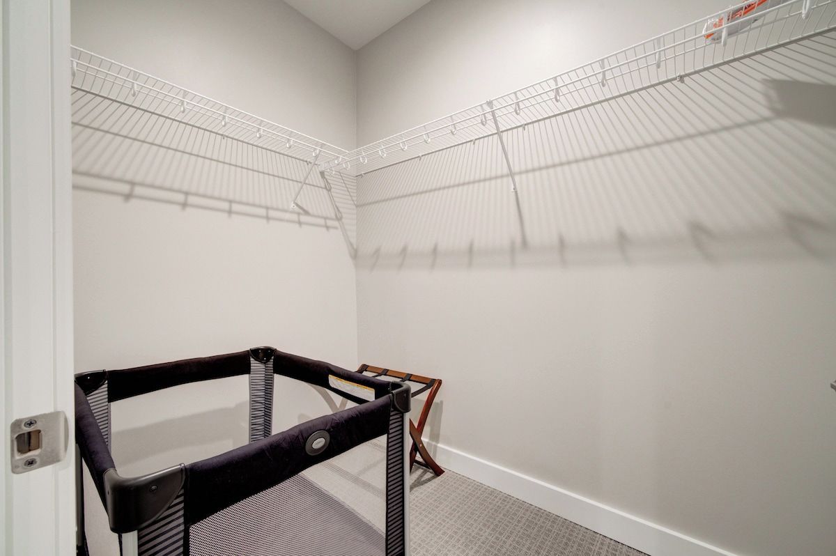 A corner of a room with a white wall, a metal shelving unit, and a black chair.