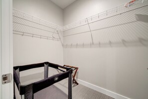 Un coin de pièce avec un mur blanc, une étagère en métal et une chaise noire.