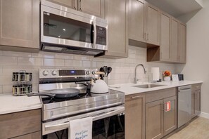 A modern kitchen with stainless steel appliances, a microwave, oven, and a sink. - Downtown Luxury Loft | Extreme Walkability (Bozeman)