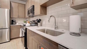 A modern kitchen with stainless steel appliances, wooden cabinets, and a white tiled backsplash. - Downtown Luxury Loft | Extreme Walkability (Bozeman)