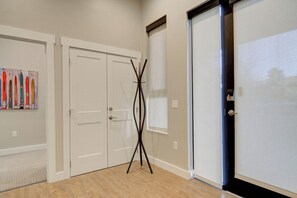 Une pièce avec une porte blanche, un porte-manteau et un tableau accroché au mur.