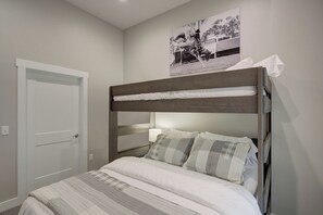 A bunk bed with a headboard, a white door, and a wall-mounted picture. - Concrete Cowboy | Downtown Luxury Livin' (Bozeman)