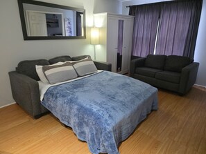 Un dormitorio con cama, sofá, armario y espejo.