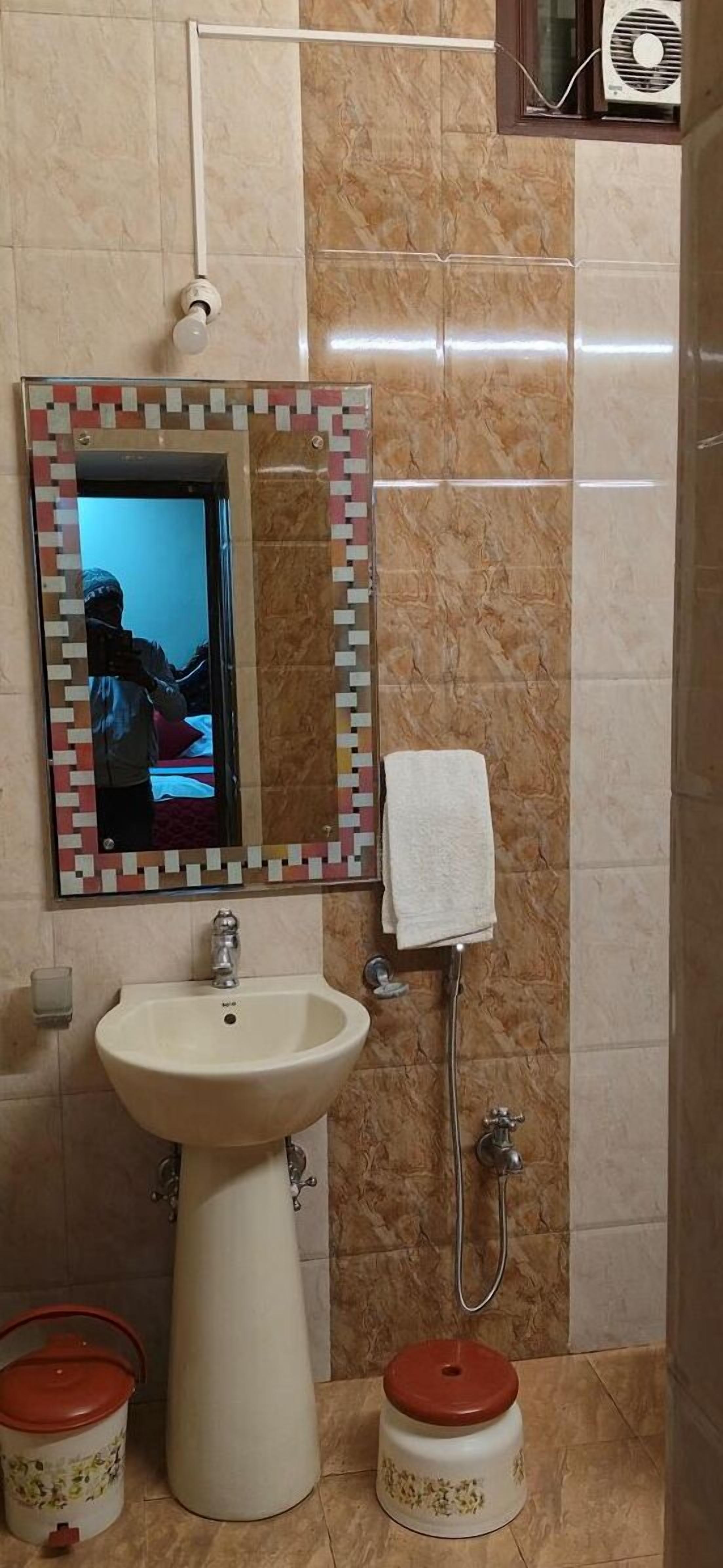 A bathroom with a sink, mirror, towel rack, and a shower.