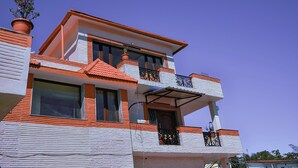 A multi-story building with a red-tiled roof, white walls, and balconies with black railings. - Astha Home Stay (Kodaikanal)