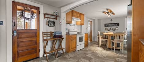 Una cocina con gabinetes de madera, una estufa blanca y una mesa de comedor con sillas.