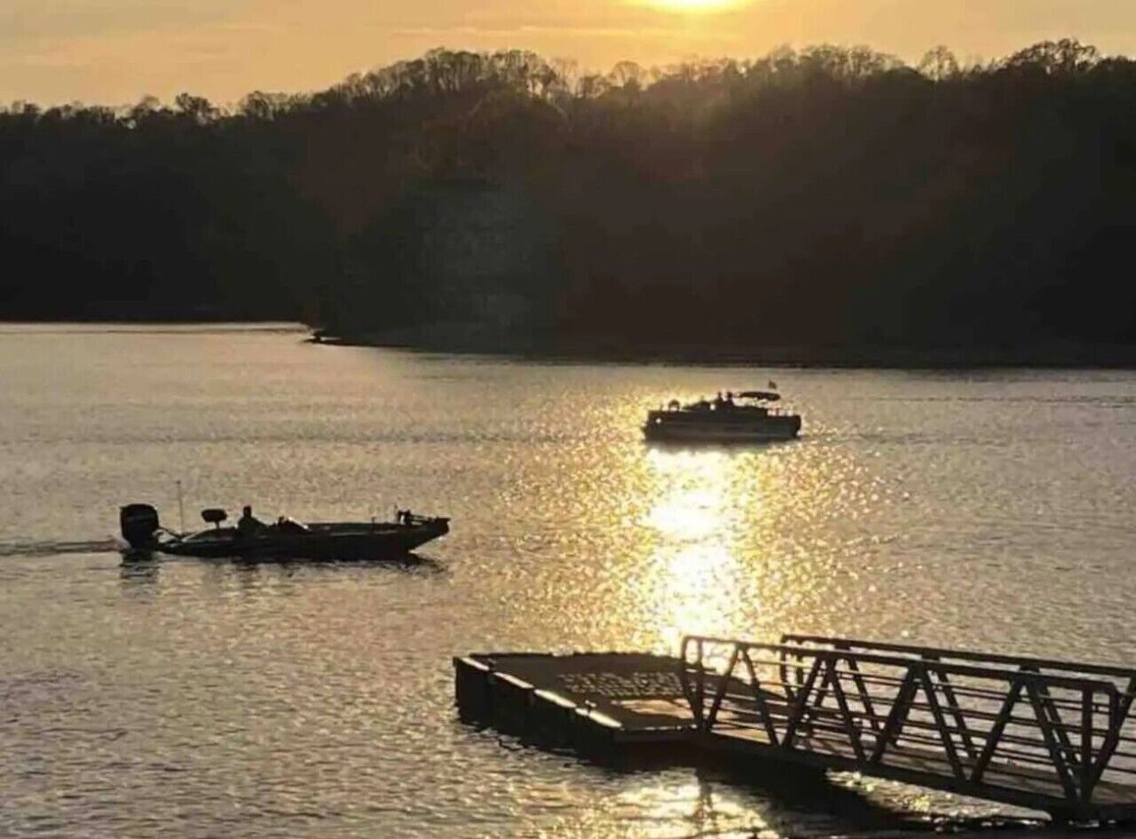 A calm body of water with a boat and a dock in the foreground.