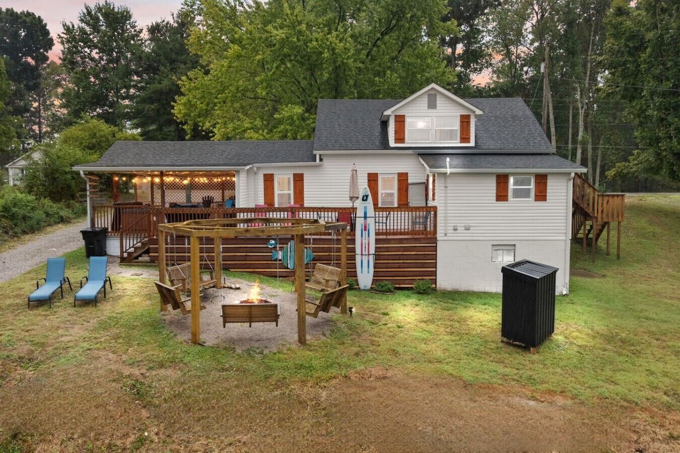 Ein Haus mit überdachter Terrasse, Sitzgelegenheiten im Freien und einer Feuerstelle.
