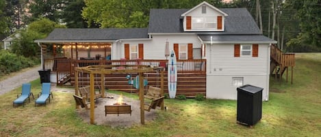Ein Haus mit überdachter Terrasse, Sitzgelegenheiten im Freien und einer Feuerstelle.