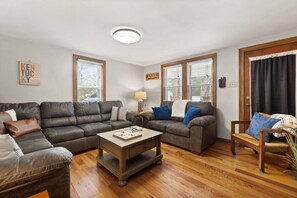 Una sala de estar con dos sofás, una mesa de centro y una silla de madera.