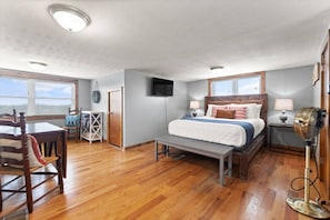 Une chambre à coucher comprenant un lit, des tables de chevet, un bureau, une chaise, un téléviseur et une fenêtre.