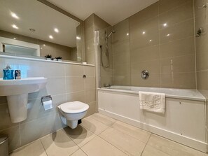 Uma casa de banho moderna com sanita, lavatório e banheira.