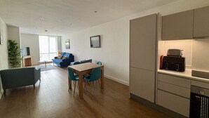 A modern living space with a dining area, a sofa, and a kitchen with a toaster.