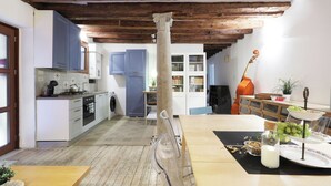 A kitchen with wooden beams, a dining area with a table set for a meal, and a violin in the background. - Spacious apartment in Venice (Venezia)