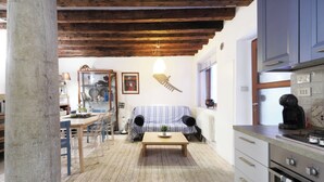 A cozy living room with a wooden coffee table, a sofa, and a kitchen area with cabinets and appliances. - Spacious apartment in Venice (Venezia)