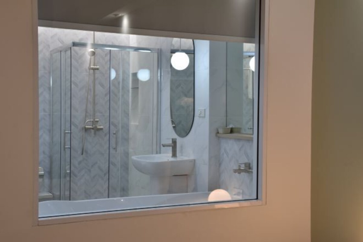 Une salle de bain moderne avec une douche à parois de verre, un lavabo et un miroir.