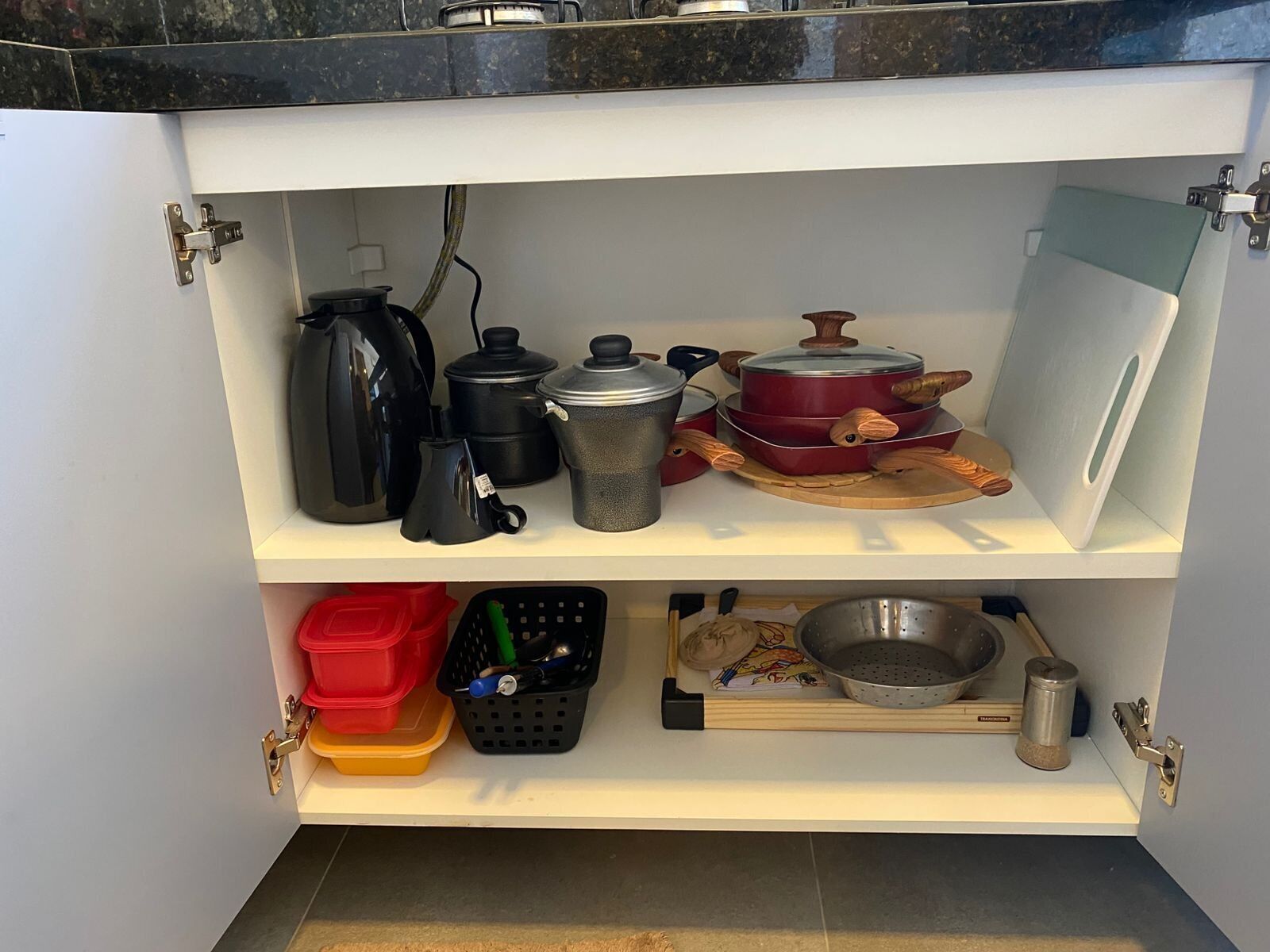 A kitchen cabinet with pots, pans, and utensils.