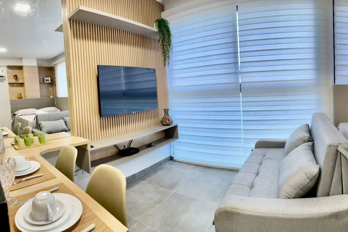 Une chambre d’hôtel moderne équipée d’un lit, d’un coin salon et d’un téléviseur fixé au mur.