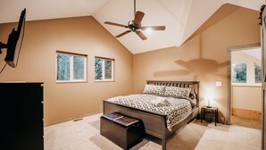 Un dormitorio con cama, ventilador de techo, ventanas y cómoda.