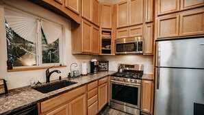 Una cocina con armarios de madera, un refrigerador de acero inoxidable, un microondas, una estufa y un lavavajillas.