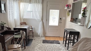 A cozy living room with a dark leather sofa, a dining table with chairs, a small kitchen area with stools, and a door with decorative glass panels. - Fabulous house with AC in charming Walla Walla (Walla Walla)