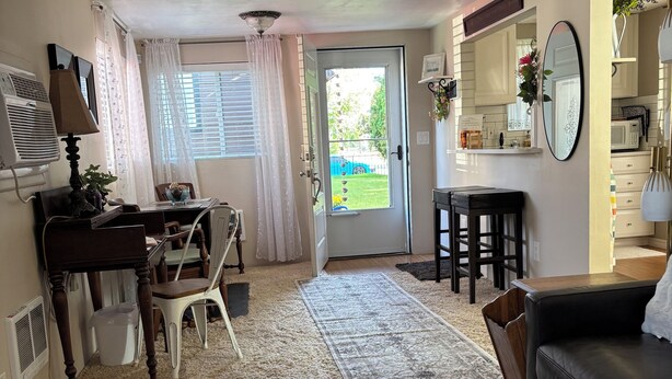 A living room with a sofa, coffee table, and a dining area with a table and chairs. A door leads to a garden. - Fabulous house with AC in charming Walla Walla (Walla Walla)