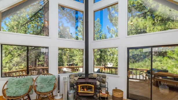 A spacious room with large windows, a stone fireplace, and wicker furniture.