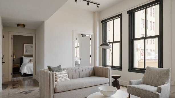 Ein modernes Wohnzimmer mit einer Couch, einem Sessel und einem runden Tisch mit einer Schale.