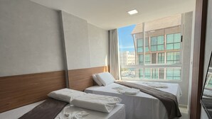 A hotel room with two beds, a large window with a city view, and a modern design. - Eco Mirage Residence by Easy Home (Ipojuca)