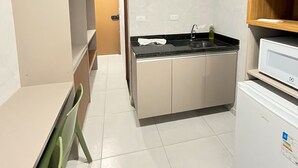 A compact kitchen with a built-in stove, a sink, and a refrigerator. - Eco Mirage Residence by Easy Home (Ipojuca)
