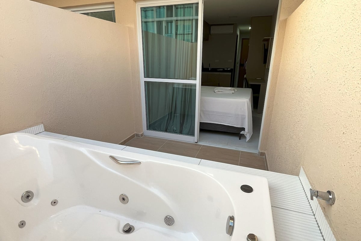 A bathroom with a large bathtub, a shower area, and a window with curtains.
