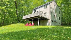 A two-story house with a balcony, surrounded by lush greenery.