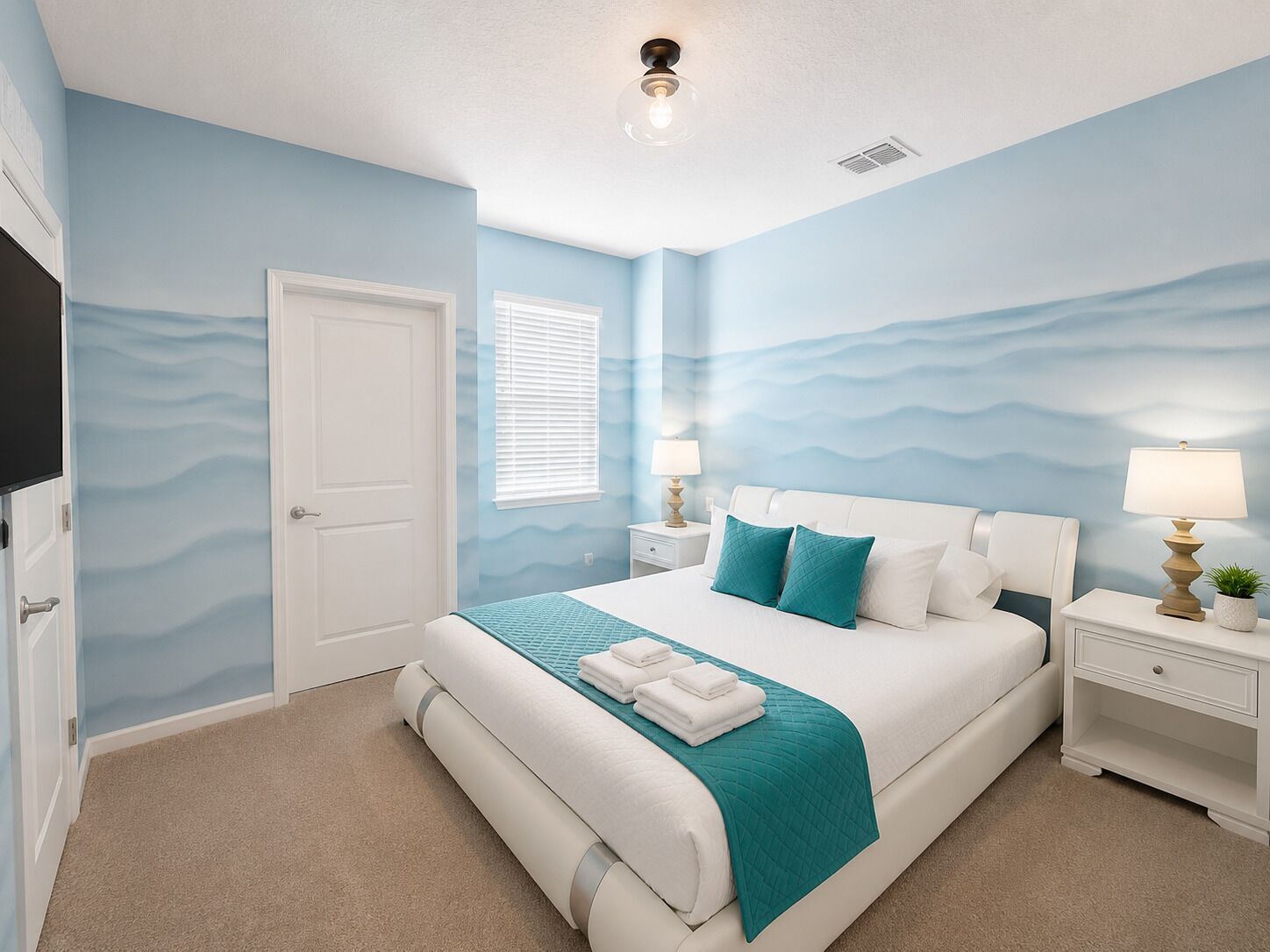A bedroom with a bed, nightstands, a TV, and a door.