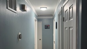 Un couloir aux murs bleu clair, doté d’un plancher en bois et de portes blanches.