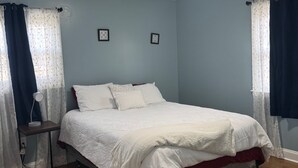 Une chambre à coucher avec un lit, une table de chevet avec une lampe et deux tableaux encadrés accrochés au mur.
