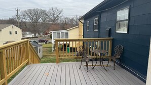 Une terrasse avec une rambarde en bois, une table et deux chaises.