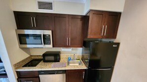 A kitchen with dark wooden cabinets, a stainless steel refrigerator, a microwave, and a dishwasher.
