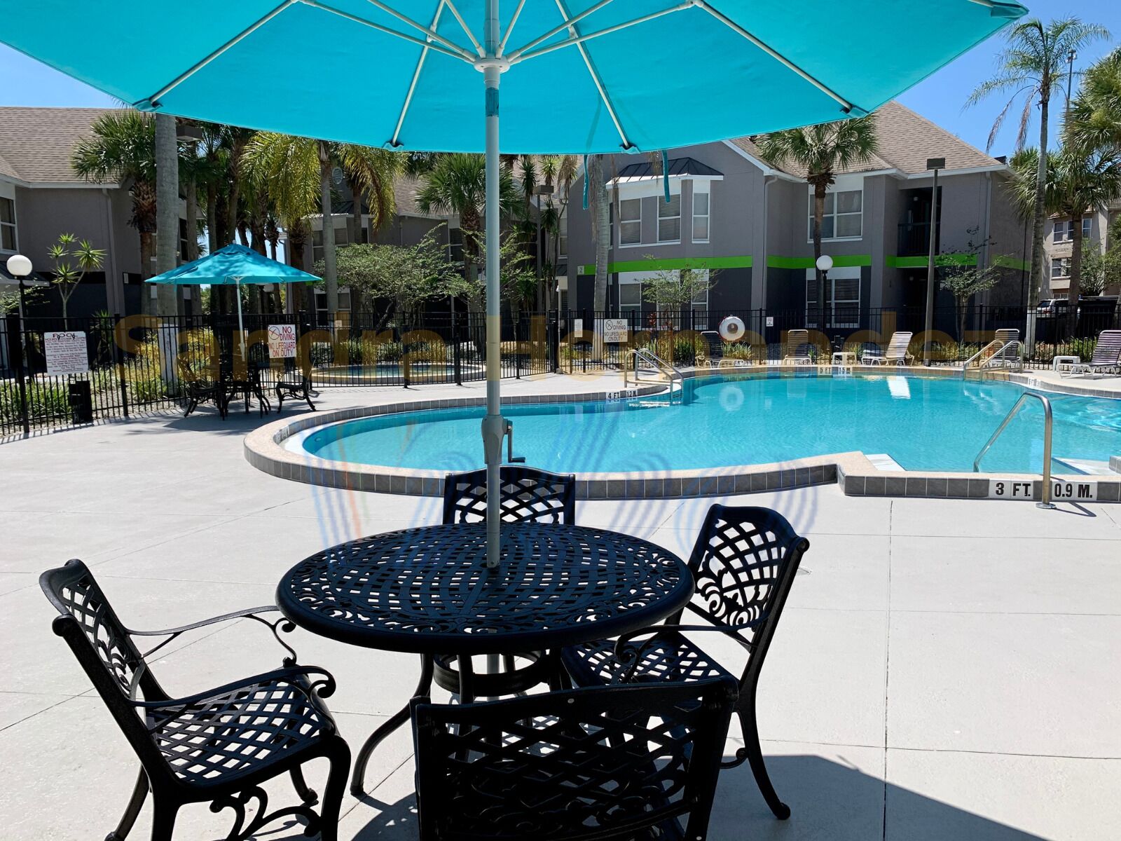 A pool area with a circular pool, lounge chairs, and a table with chairs.