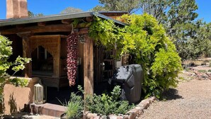 A rustic cabin with a wooden porch, a grill, and a hanging vine. - 2br Historic Adobe - 2acr Homestd A/C Exquisite NEW to VRBO! (Santa Fe)