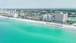 Vista aérea de una zona costera con un hotel frente a la playa, edificios altos y una playa de arena.