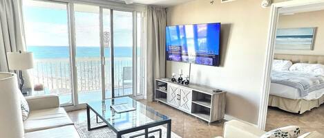 Camera d'albergo con balcone, televisore a schermo piatto, divano, tavolino da caffè e letto.