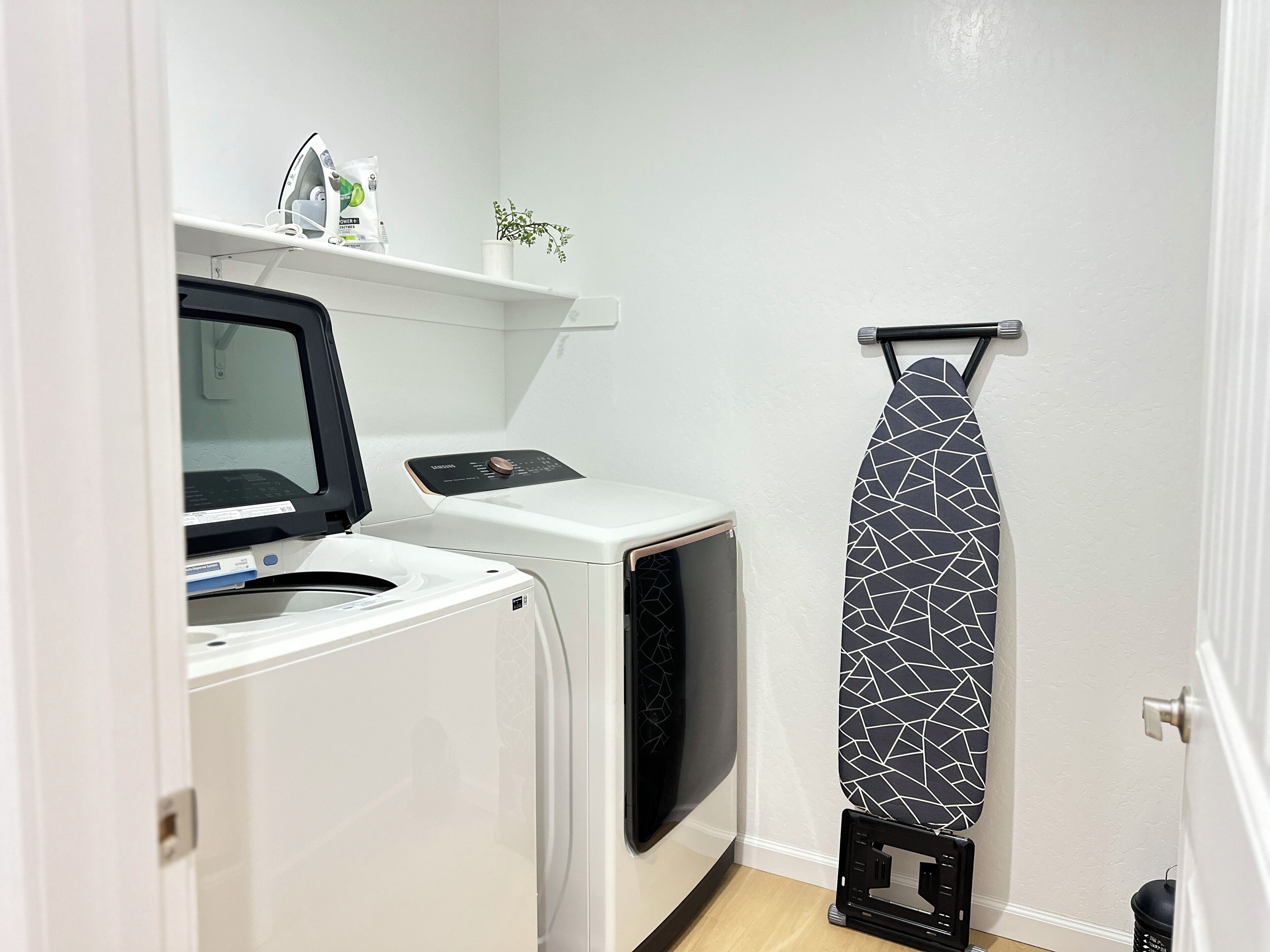 A laundry area with a washing machine, dryer, and an iron stand.