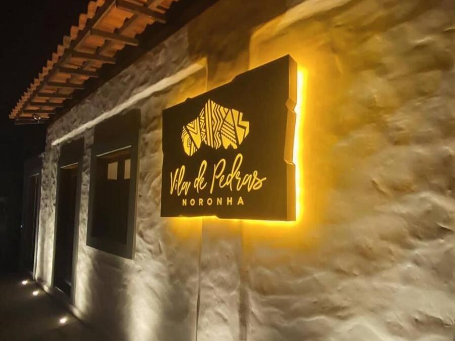 Edifici de pedra amb un cartell que diu "Vila de Pescadores Noronha".